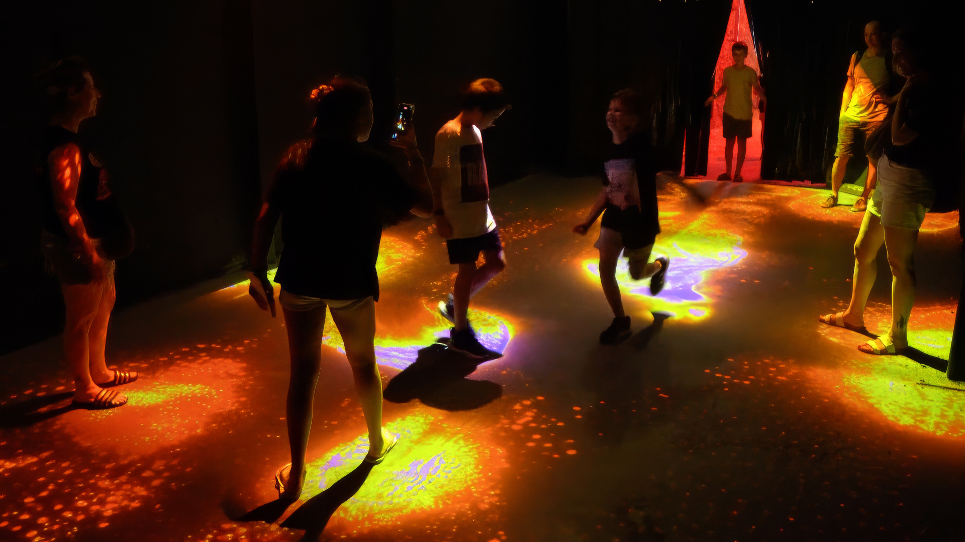Visitors walking on the Slices floor lit with orange and yellow patches of light