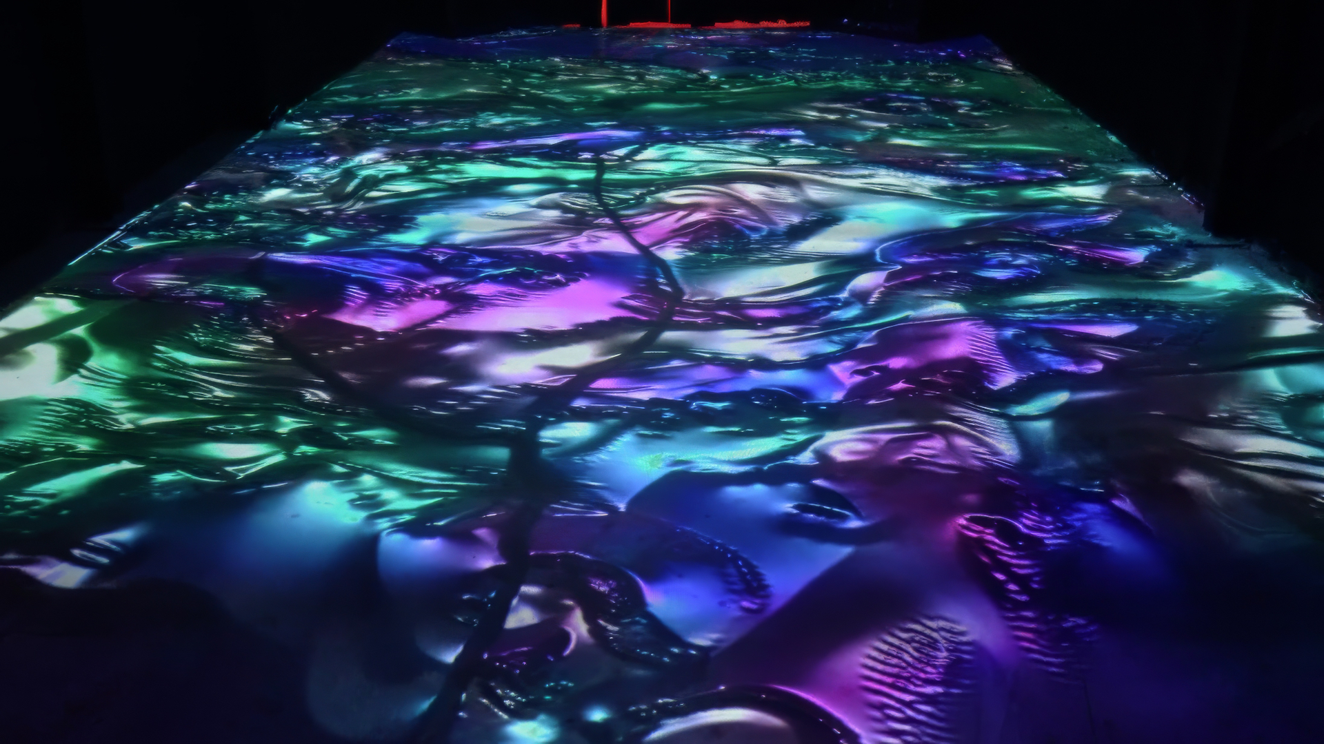 View along a projected floor with flowing purple, blue and green patterns